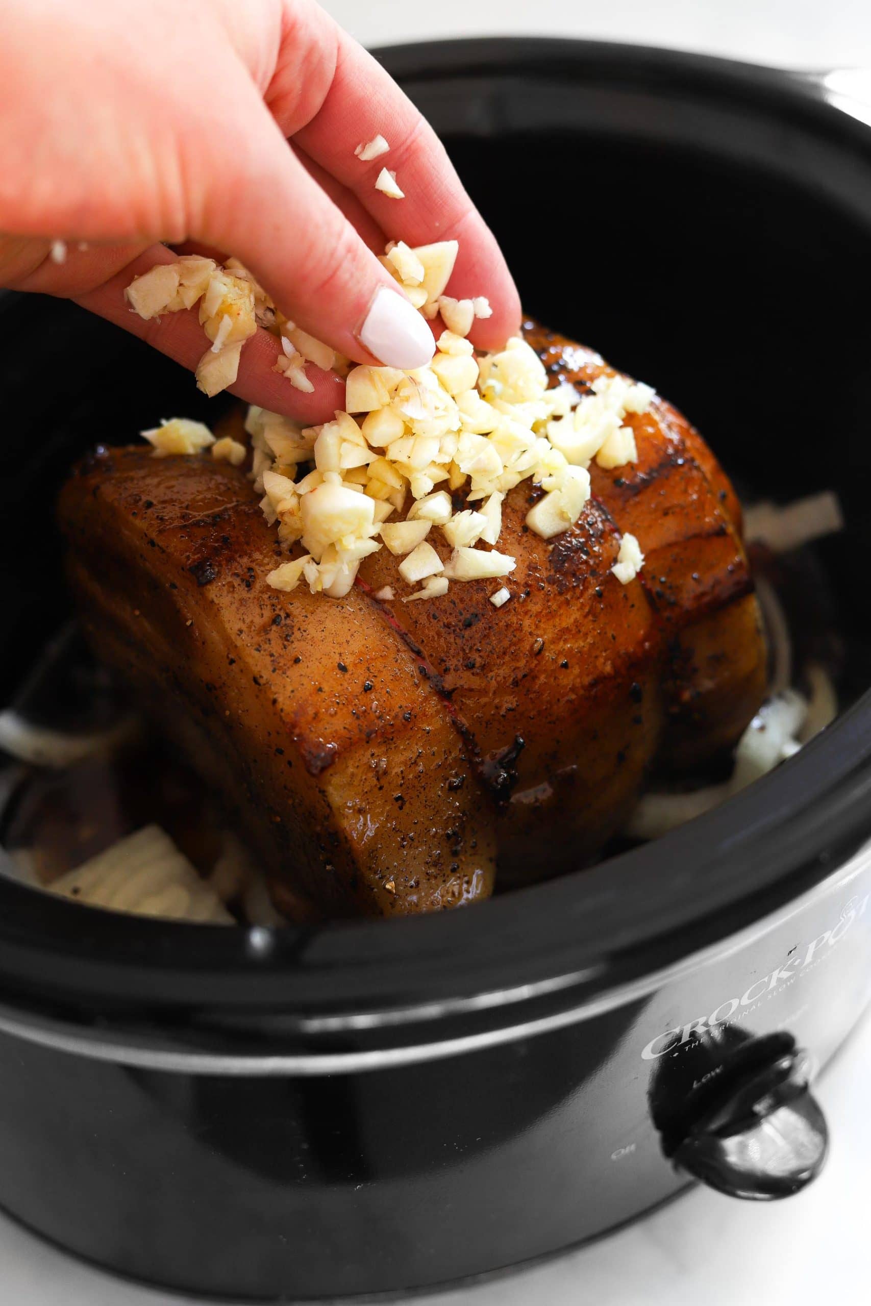 adding garlic on top of pork loin